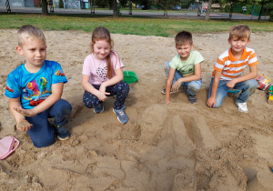 Dzieci budują piaskowe zwierzęta.