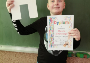 Chłopiec trzyma dyplom i literkę H