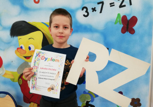 Chłopiec trzyma dyplom i dwuznak RZ