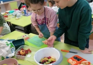 Uczniowie wykonują sałatkę owocową