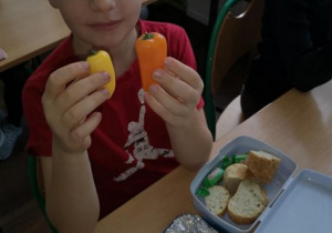 Uczeń pokazujacy swoje warzywne śniadanie