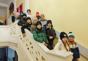 Uczniowie po spektaklu stoją na ozdobnych schodach