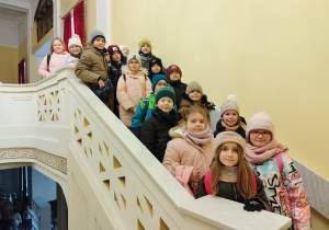 Uczniowie po spektaklu stoją na ozdobnych schodach