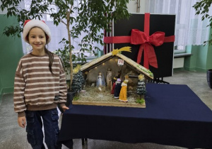 Dziewczynka pozuje przy swojej szopce.