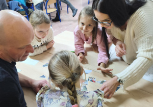 Rodzice wspólnie z dziećmi rozwiązują bożonarodzeniowe zadania.
