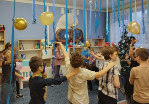 Dzieci robią węża, tańcząc z balonami