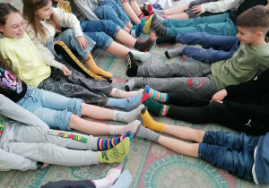 Uczniowie z klasy 3a siedzą w kole pokazując różnokolorowe skarpety.