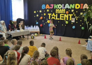 Chłopiec prezentuje sportowe sztuczki z piłkami.