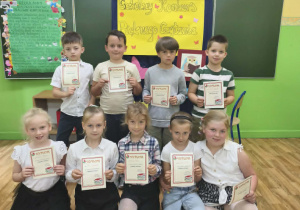Uczniowie klas 1 trzymają dyplomy za udział w szkolnym konkursie "Pięknie czytam".