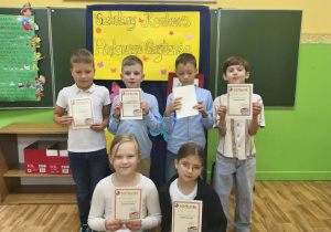 Uczniowie klas 2 trzymają dyplomy za udział w szkolnym konkursie "Pięknie czytam".