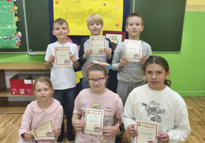 Uczniowie klas 3 trzymają dyplomy za udział w szkolnym konkursie "Pięknie czytam".