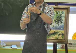 Pan pokazuje model człowieka wykonany z drewna.