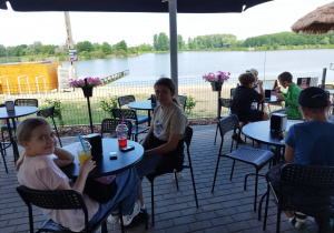 Dzieci siedzą w SurfCafe nad Zalewem Miejskim i jedzą lody