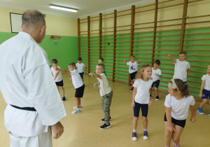 Dzieci powtarzają ciosy karate za trenerem