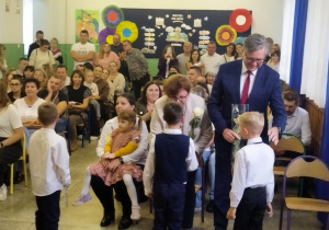 Pierwszoklasiści wręczają kwiaty zaproszonym gościom.
