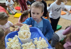 Pani rozdaje dzieciom popcorn