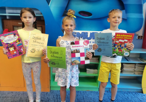 Troje dzieci trzyma dyplomy oraz nagrody książkowe za klasowy Konkurs Liczenia