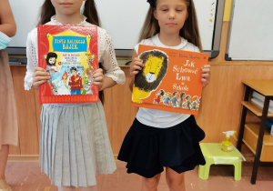 Dwie dziewczynki trzymają nagrody i dyplomy za szkolny Konkurs Pięknego Czytania