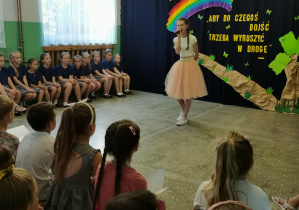 Uczennic klasy VIII Amelia Jaworowska śpiewa, stojąc na środku holu szkoły