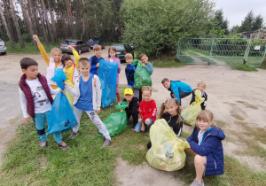 14 dzieci pozuje do zdjęcia z workami pełnymi uprzątniętych przez siebie śmieci.