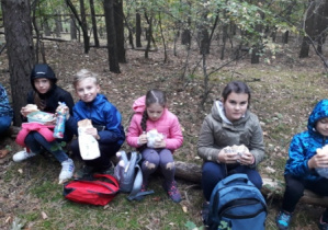 dzieci siedzą w lesie na konarze