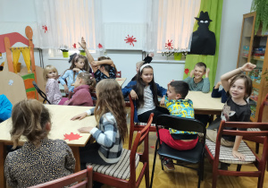 Dzieci siedzą przy stolikach i zgłaszają swoje pomysły.