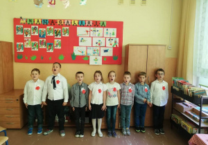 Dzieci śpiewają hymn Polski w pozycji na baczność.
