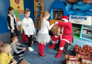 Mikołaj wręcza upominki dziewczynkom.