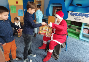 Mikołaj wręcza upominki chłopcom.