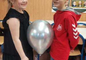 Dwoje dzieci tańczy z balonikiem.