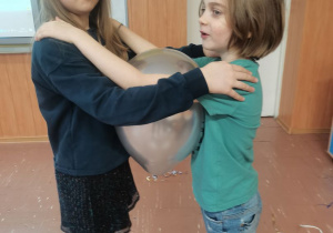 Dwoje dzieci tańczy z balonikiem.