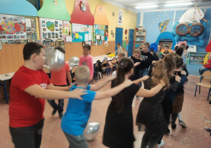 Dzieci tańczą na środku klasy tworząc węża.