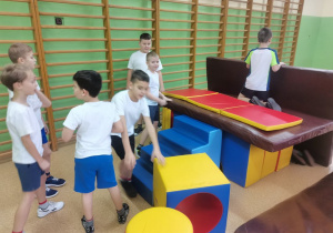 Chłopcy budują "dom" z materacy do ćwiczeń gimnastycznych.