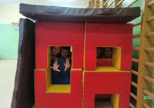 Chłopcy pozują w "domku" zbudowanym z materacy do ćwiczeń gimnastycznych.