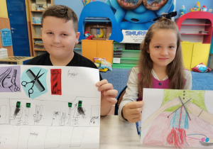 Dwoje dzieci prezentuje swoje prace konkursowe.