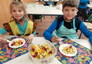 2 dzieci prezentuje wykonaną własnoręcznie sałatkę owocową.