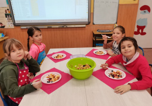 4 dziewczynki prezentują wykonaną własnoręcznie sałatkę owocową.
