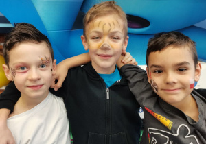 3 chłopców prezentuje swoje pomalowane twarze.