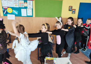 Dzieci z klasy II b w korowodzie tańczą do muzyki karnawałowej.