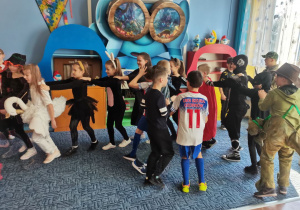 Dzieci z klasy II b w korowodzie tańczą do muzyki karnawałowej.