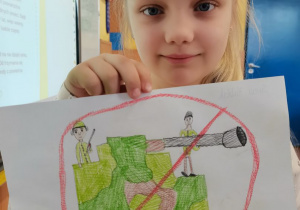 Dziewczynka prezentuje wykonany przez siebie plakat.