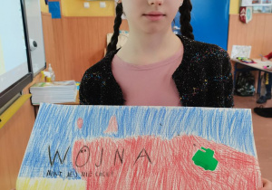 Dziewczynka prezentuje wykonany przez siebie plakat.