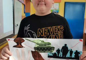 Chłopiec prezentuje wykonany przez siebie plakat.