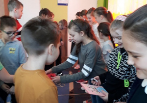 Chłopcy wręczają koleżankom własnoręcznie wykonane laurki z okazji Dnia Kobiet.