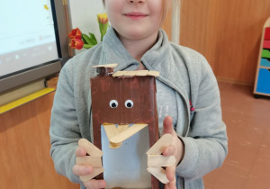 Dziewczynka prezentuje swój karmnik wykonany z pudełka po mleku.