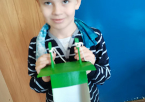 Chłopiec prezentuje swój karmnik wykonany z pudełka po mleku.