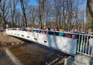 Uczniowie stoją na nowym mostku nad Bzurą.