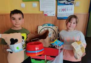 Dwoje dzieci prezentuje przyniesione przez siebie dary.