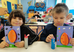 2 dzieci prezentuje swoje prace plastyczne.