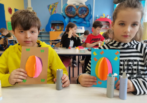 2 dzieci prezentuje swoje prace plastyczne.